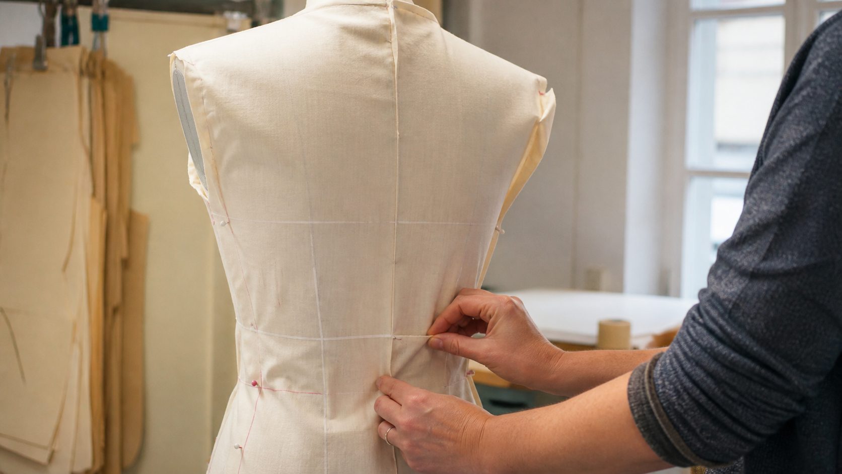 Toile de vêtement épinglée sur un buste de couture avec patron papier et outils d’ajustement
